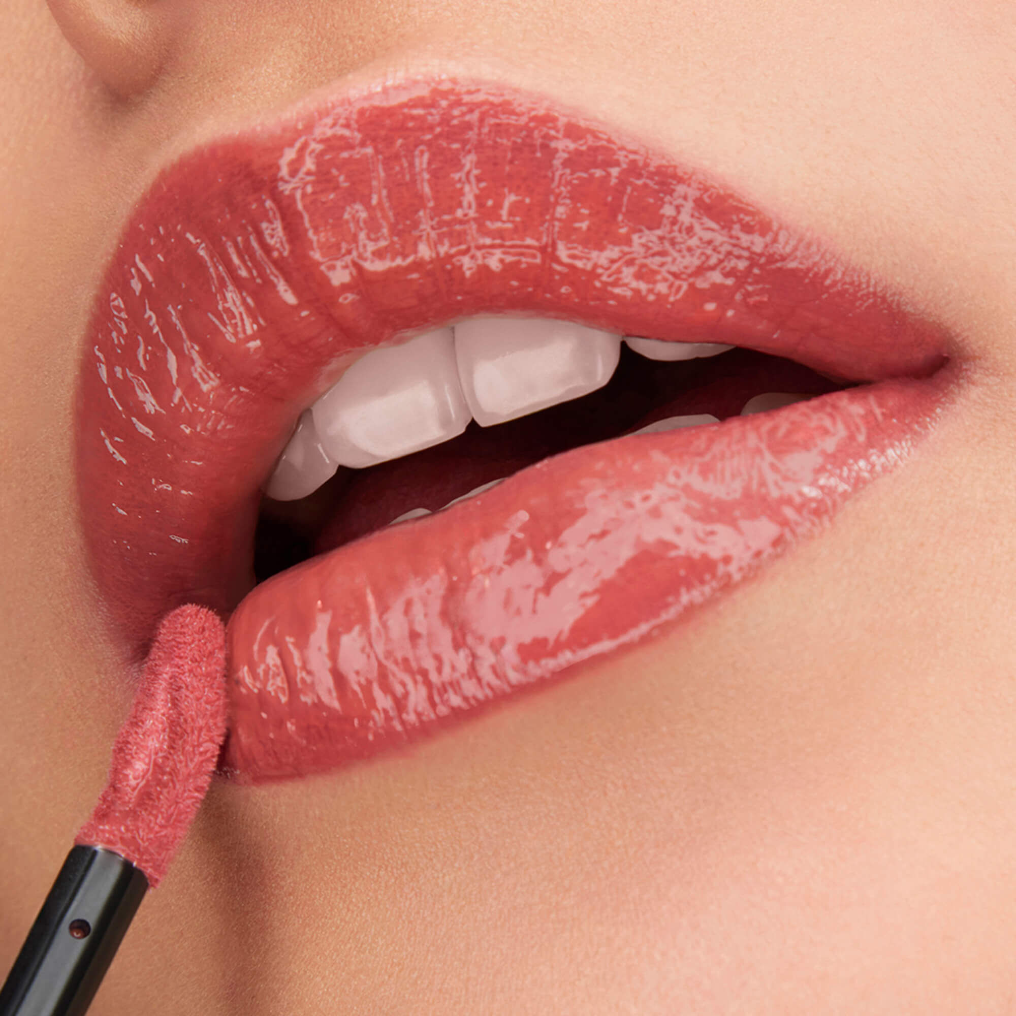 Eine Nahaufnahme glanzender, nude-rosa Lippen, die mit dem Lancome L'Absolu Rouge Glaze Tintation-Applikator fur ein hochglanzendes, glasiertes Finish verstarkt werden.
