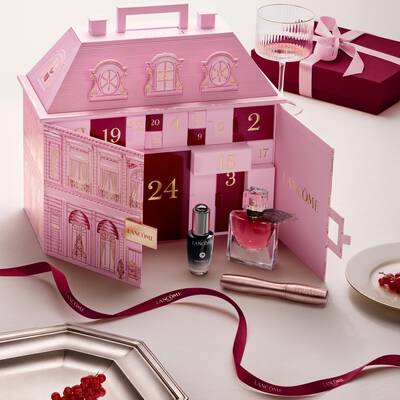 Ein geoffneter, pinkfarbener Lancome-Palast Adventskalender, prasentiert mit Beauty-Produkten und einer roten Schleife.