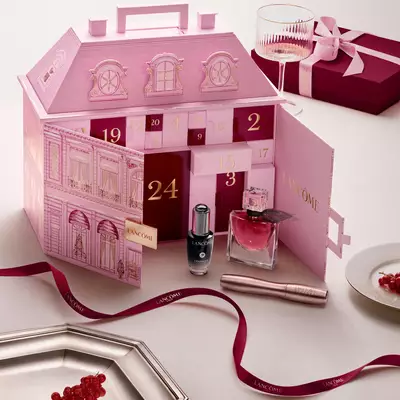 Ein geoffneter, pinkfarbener Lancome-Palast Adventskalender, prasentiert mit Beauty-Produkten und einer roten Schleife.