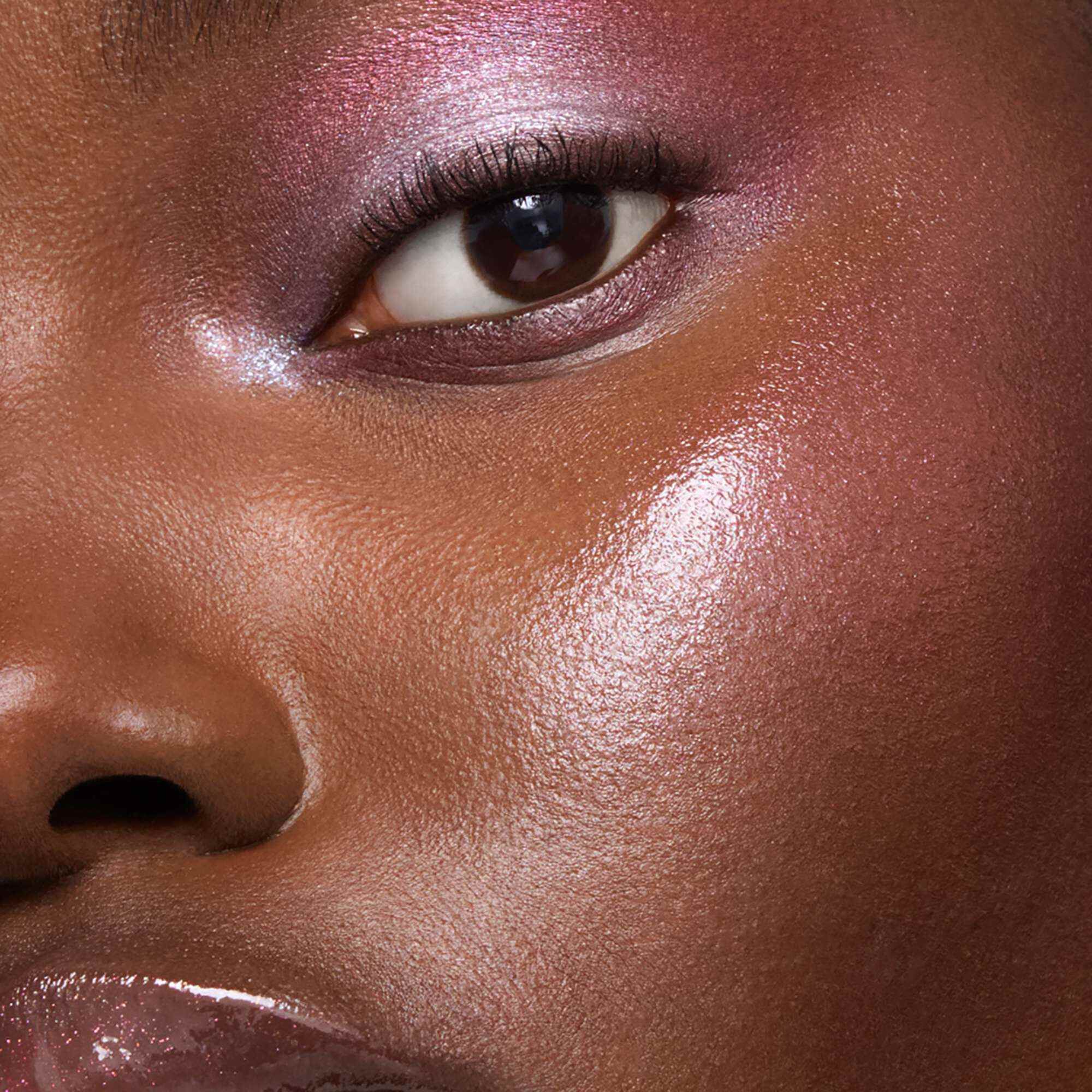 Ein Make-up-Look in Nahaufnahme mit schimmerndem rosa Lidschatten und strahlendem Highlighter auf den Wangen.
