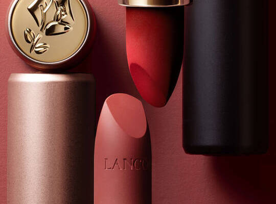 Eine Kollektion von Lancome Make-up-Produkten, darunter eine Lidschattenpalette, ein Kompaktpuder und ein roter Lippenstift, alle in eleganter rosa-goldener Verpackung.
