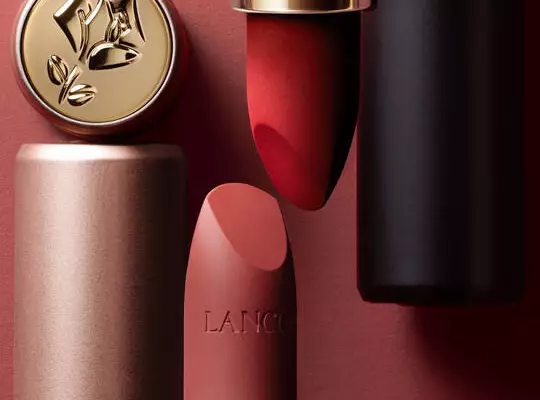 Eine Kollektion von Lancome Make-up-Produkten, darunter eine Lidschattenpalette, ein Kompaktpuder und ein roter Lippenstift, alle in eleganter rosa-goldener Verpackung.