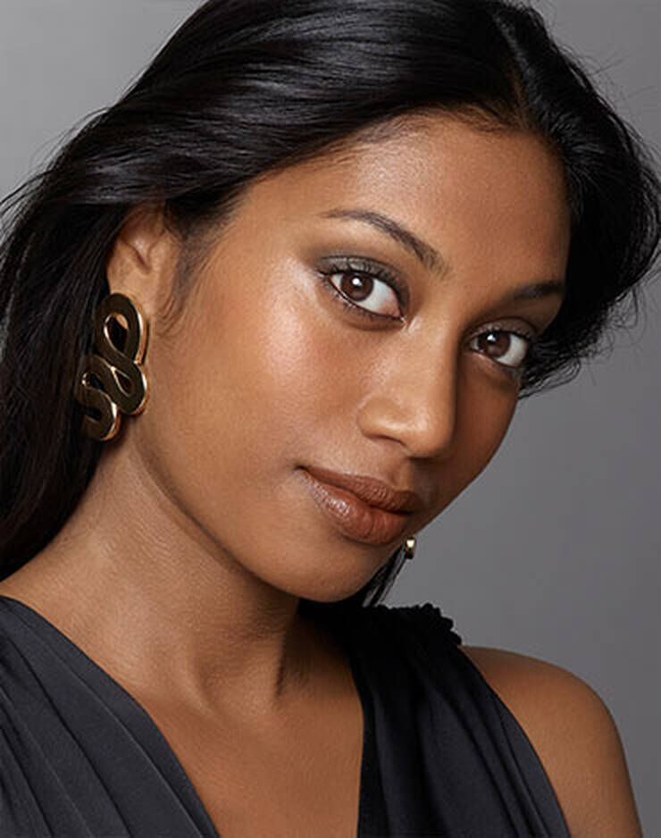 Eine Frau mit dunklen Augen und dunklen Haaren und einem leicht gelben oder pfirsichfarbenen Hautton.