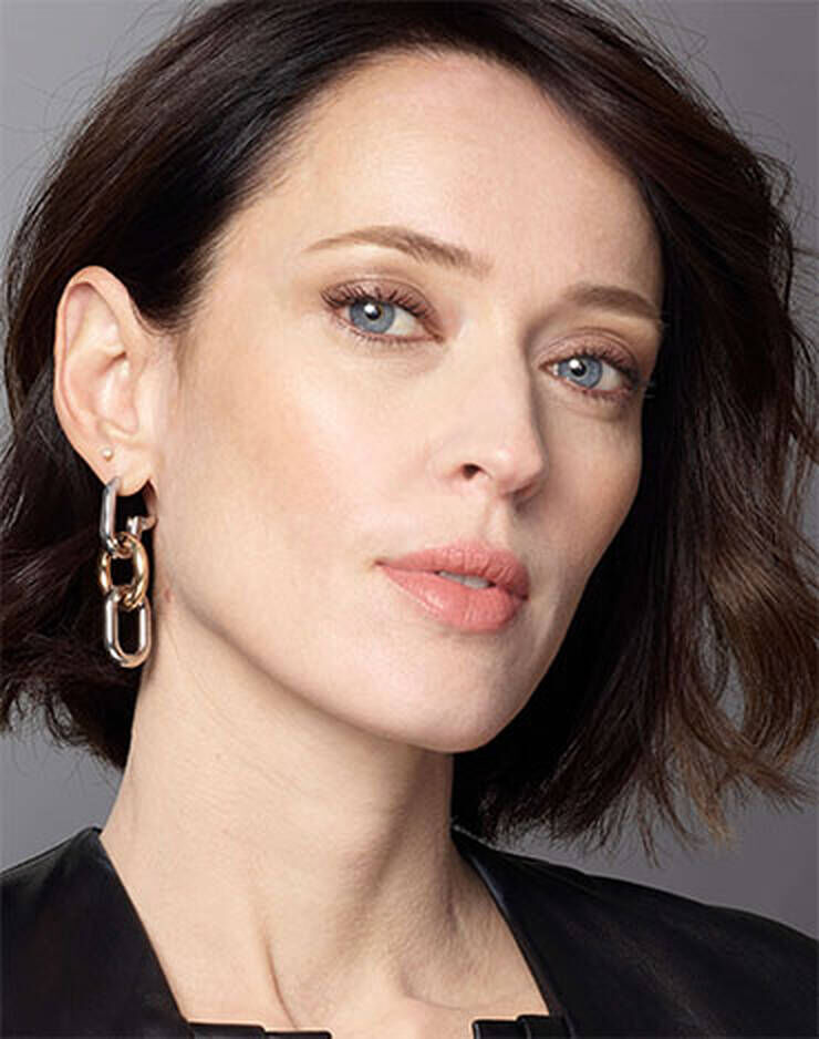 Eine Frau mit hellen Augen und braunen Haaren und einem leichten rosa, roten oder blaulichen Hautton.