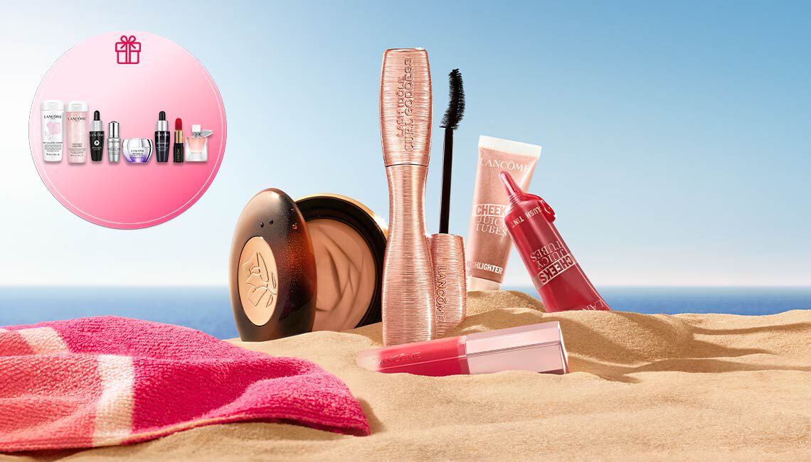 Lancome Sommer-Make-up im Sand mit einem runden Geschenk-Symbol auf der linken Seite und viel freiem Platz vor blauem Himmel und Meer rechts