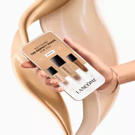 Alt-Text: Eine Hand halt ein Smartphone, das eine App zur Farbauswahl fur Makeup zeigt, umgeben von flussiger Foundation in cremigen Tonen.