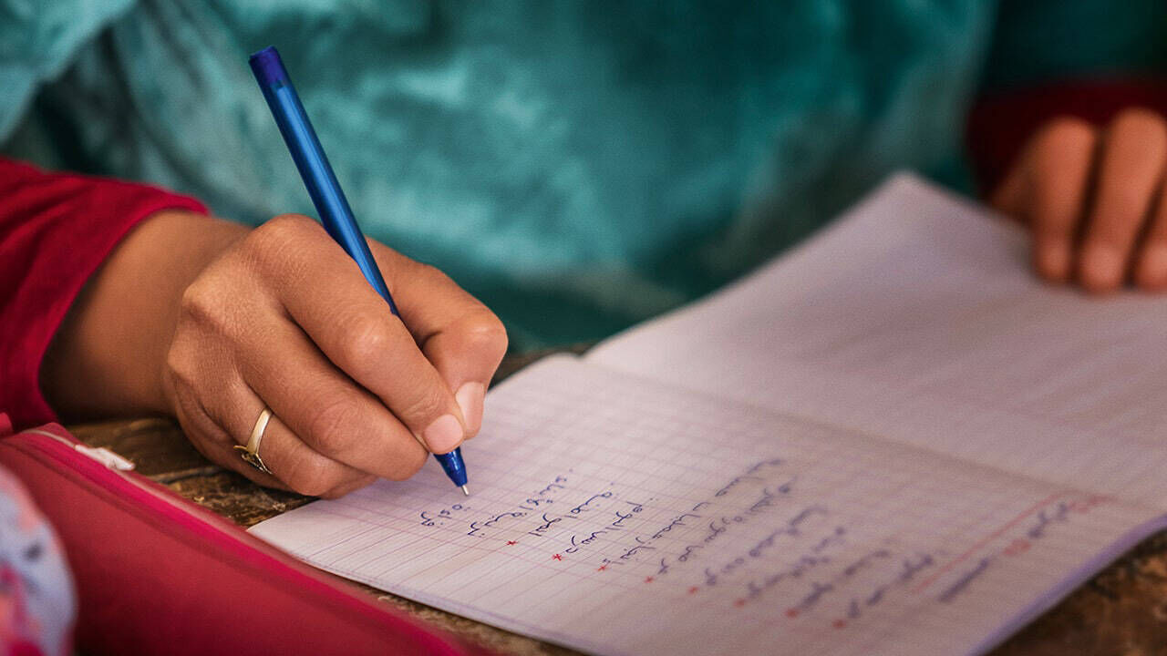 Eine Hand schreibt mit einem Stift in einem Notizheft.