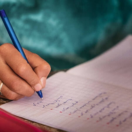 Eine Hand schreibt mit einem Stift in einem Notizheft.