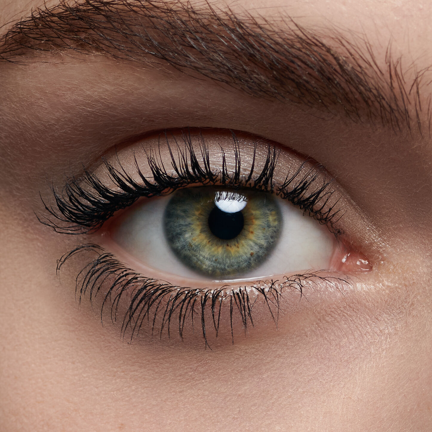 Nahaufnahme eines menschlichen Auges mit leuchtend gruner Iris und langen Wimpern.