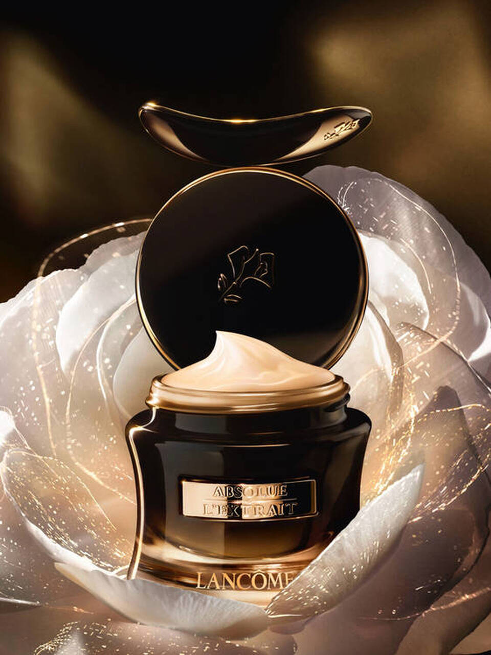 Eine elegante Creme von Lancome in einem luxuriosen Glasbehalter, umgeben von einer weißen Blute.