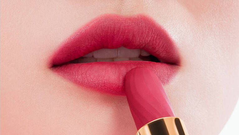 Nahaufnahme von Lippen in sanften Rosa-Tonen, wahrend ein Lippenstift aufgetragen wird.