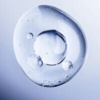 Eine klare Wasserblase mit kleinen Luftblasen auf einem sanften, blauen Hintergrund.