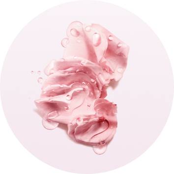 Helle, rosa Gesichtscreme mit Wassertropfen auf weißem Hintergrund, in kreisformiger Anordnung.