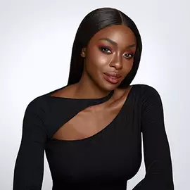 Portrat einer Frau mit glatten, langen Haaren, die ein schwarzes Oberteil tragt und intensives Make-up hat. Ihr Gesicht zeigt Selbstbewusstsein und Eleganz.