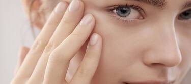 Eine Nahaufnahme eines jungen Gesichts mit blauen Augen, das sanft mit einer Hand beruhrt wird.