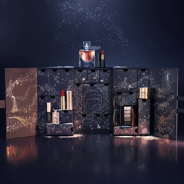 Ein geoffneter Adventskalender mit verschiedenen Kosmetikprodukten, wahrend eine Hand ein Parfum entnimmt. Der Kalender hat ein elegantes, dekoratives Design und ist vor einem dunklen, sternenubersaten Hintergrund platziert.