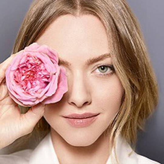 Dekoratives Bild: Nahaufnahme einer Frau, die eine Blume vor ihr rechtes Auge halt