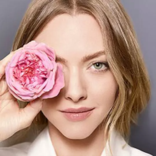 Dekoratives Bild: Nahaufnahme einer Frau, die eine Blume vor ihr rechtes Auge halt