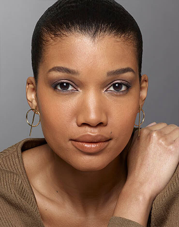 Eine Frau mit braunen Augen und braunen Haaren und einem leicht gelben oder pfirsichfarbenen Hautton