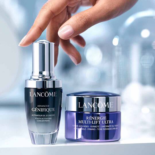 Advanced Genifique Serum und Renergie Multi Lift Ultra nebeneinander, Hand greift nach dem Serum