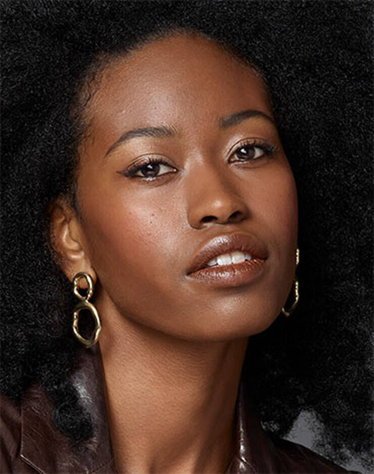 Eine Frau mit dunklen Haaren und leichten rosa, roten oder blaulichen Hautton.