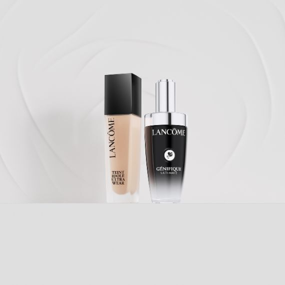 Zwei Lancome-Produkte, die Teint Idole Ultra Wear Foundation und das Genifique Ultimate Serum, stehen nebeneinander vor einem weißen Hintergrund mit subtilen grauen Wirbelmustern.