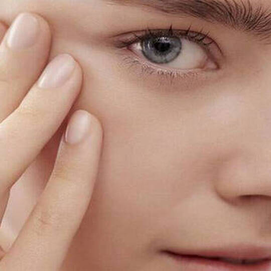 Eine Frau mit dramatischem geflugelten Eyeliner halt ein weißes Wattepad nahe ihrem Auge.
