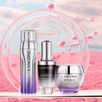 Drei Lancome Hautpflegeprodukte auf einem rosa Hintergrund: ein Serum und zwei Cremes.