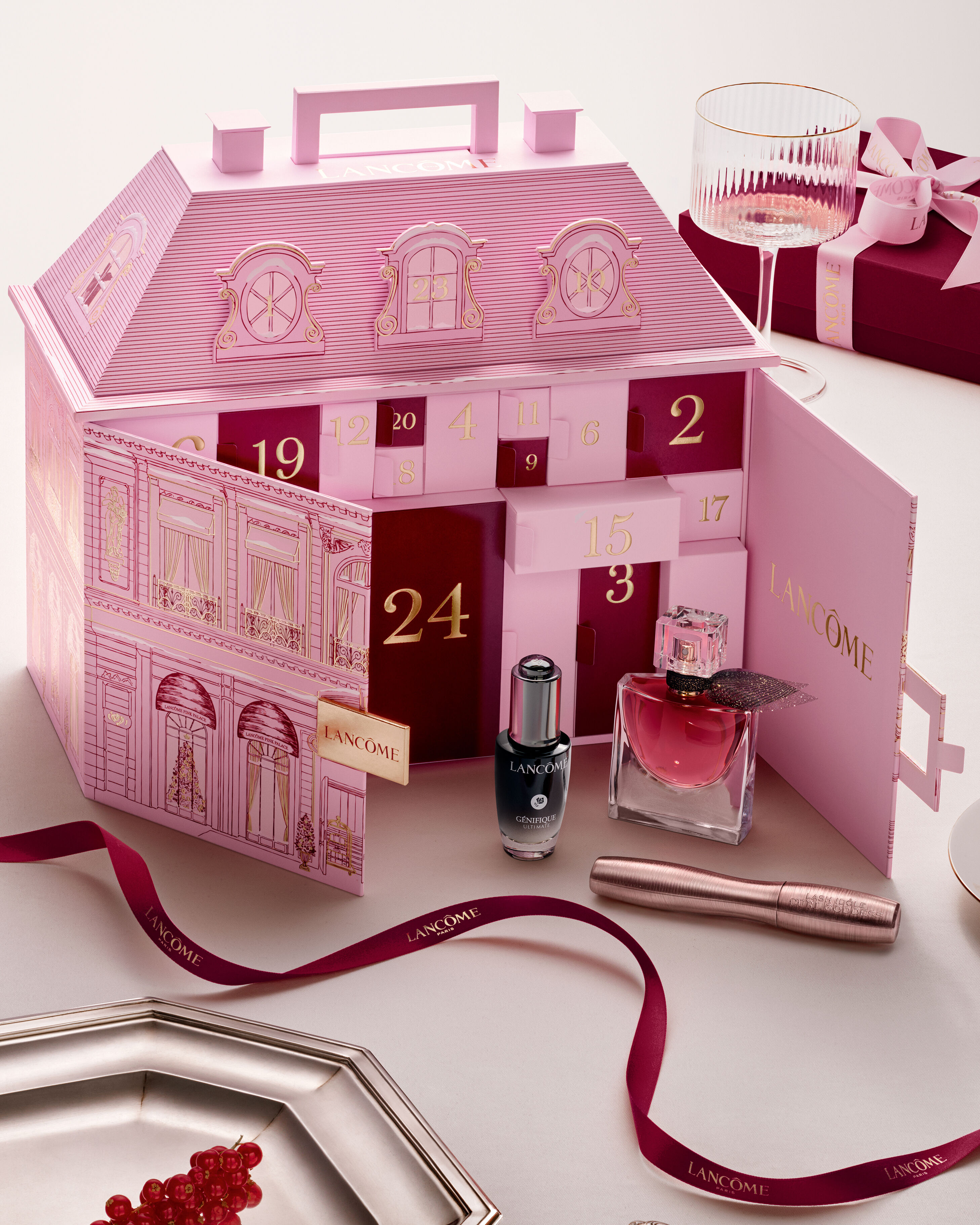 Eine Person tragt mehrere elegante Geschenkboxen von Lancome, die in dunklen Farben mit goldenen Akzenten gestaltet sind.