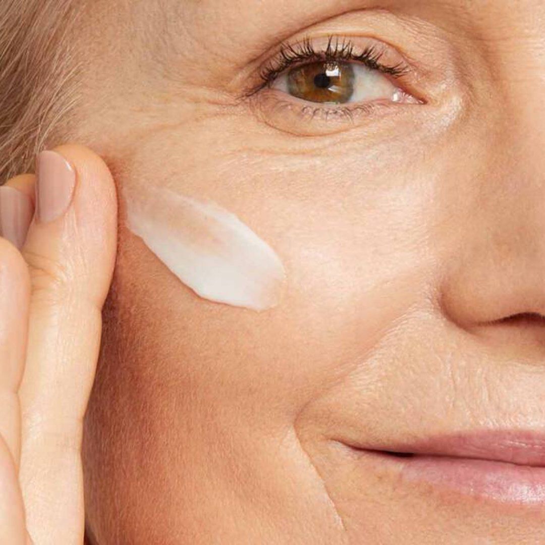 Dekoratives Bild: Nahaufnahme einer Frau, die Creme unter ihrem Auge auftragt