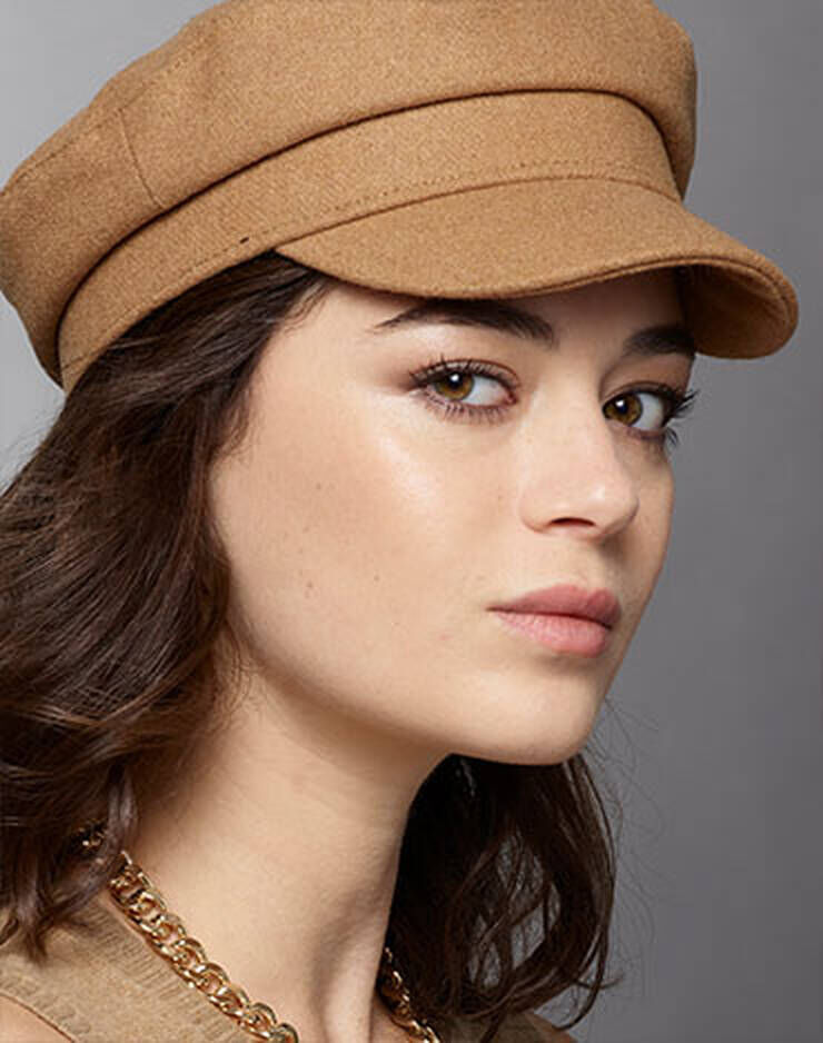 Eine Frau mit braunen Augen und braunen Haaren und einem leicht gelben oder pfirsichfarbenen Hautton