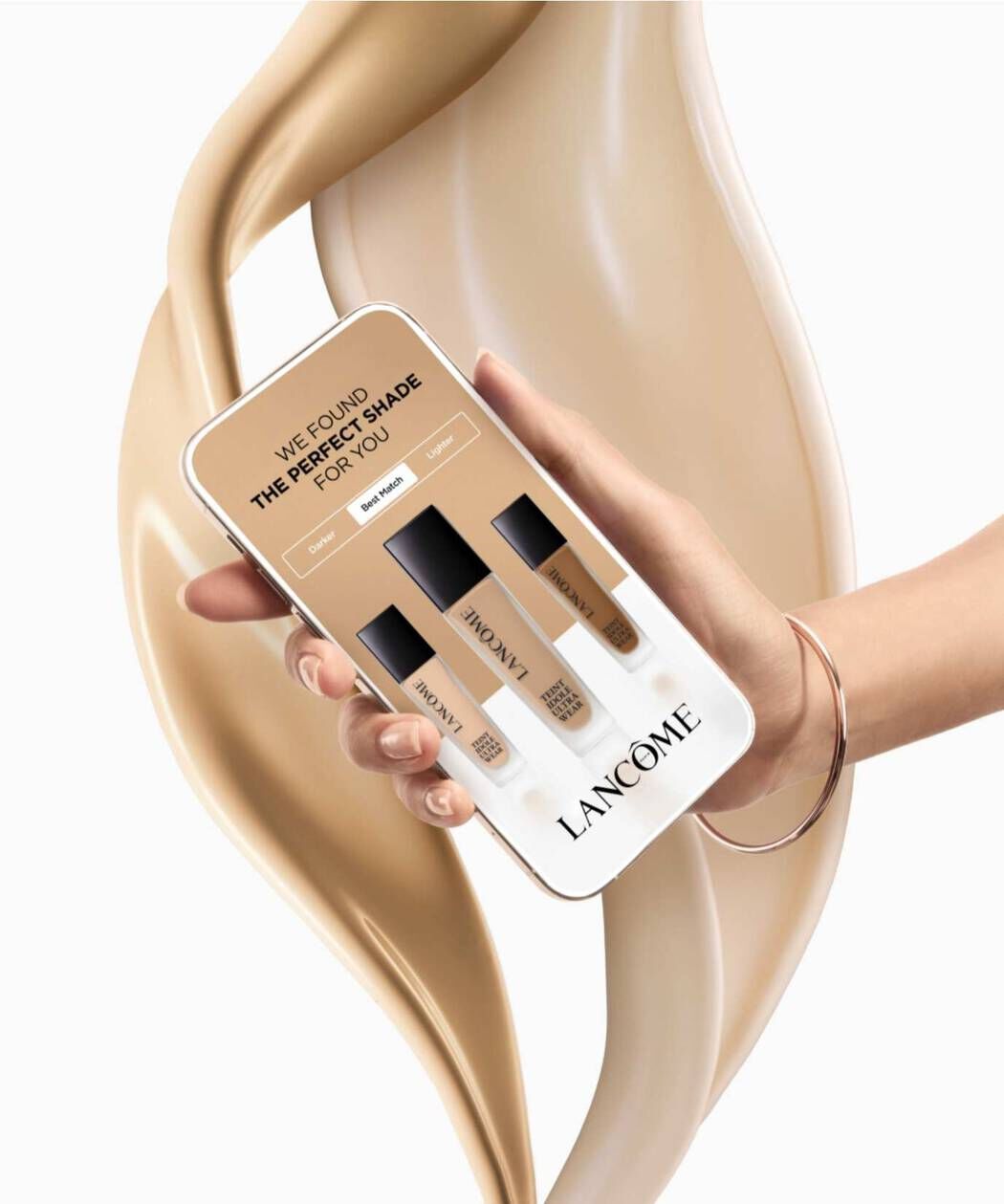Eine Hand halt ein Smartphone, das eine Anzeige mit verschiedenen Foundation-Tonen von Lancome zeigt, um den perfekten Farbton zu finden. Im Hintergrund ist eine cremige, beige Textur zu sehen.
