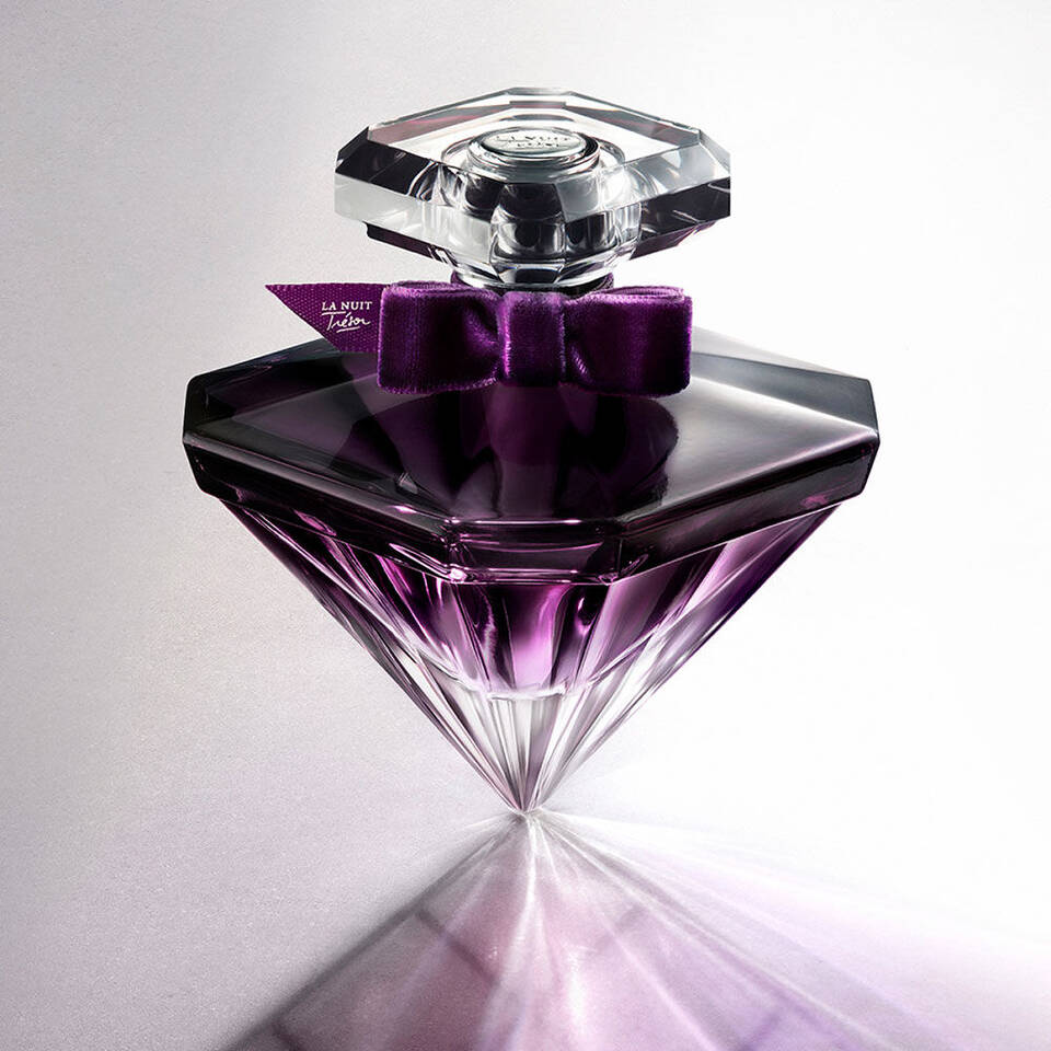 Ein eleganter Parfumflakon in Diamantform mit lila Farbverlauf und einer schwarzen Seidenschleife.