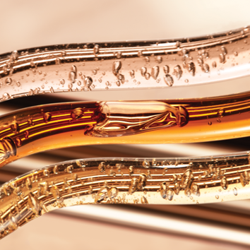 Nahaufnahme von flussigen, goldfarbenen Rohren mit Blasen, die eine elegante und moderne Asthetik vermitteln.