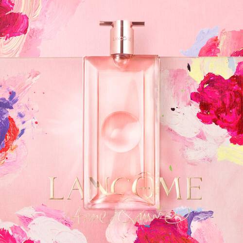 Ein eleganter Flakon von Lancome, umgeben von bunten Blumenmustern auf rosa Hintergrund.