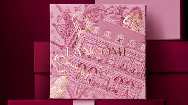 Rosa Lancome-Geschenkbox mit festlichem Muster vor einem burgunderroten Hintergrund.