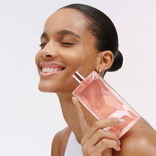 Nahaufnahme einer Frau mit Parfum-Flasche in der Hand