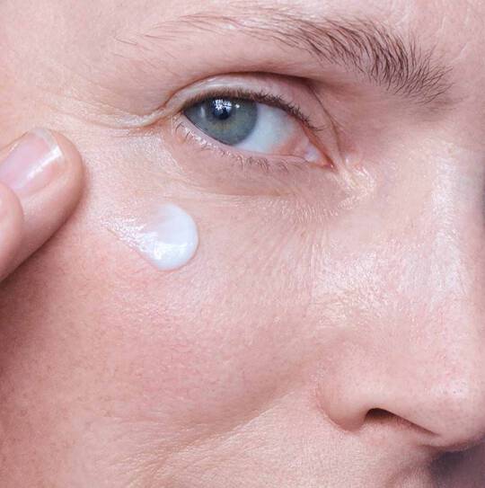 Ein Auge, darunter cremt eine Hand ein