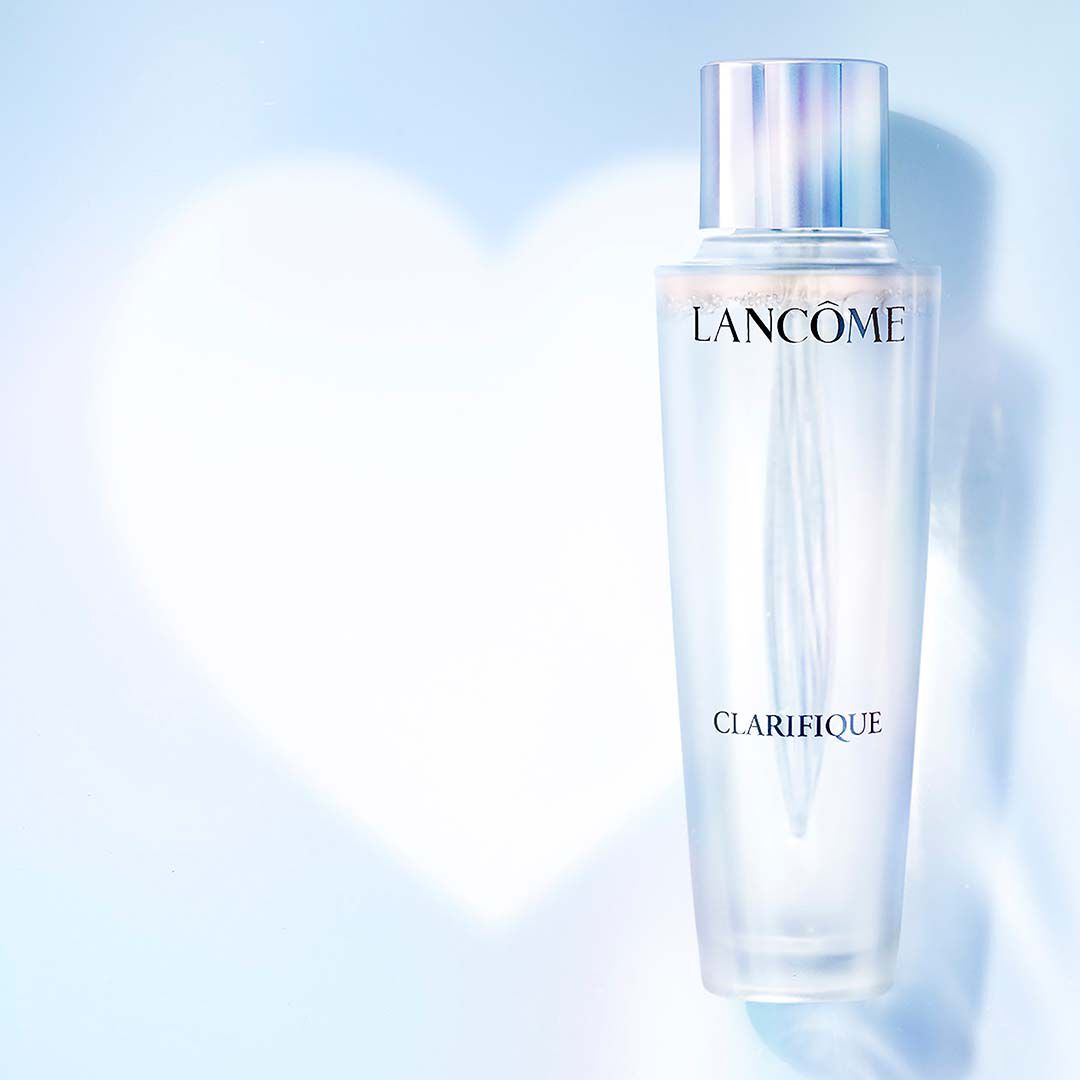 Lancome Clarifique Essenzflasche auf hellblauem Hintergrund mit herzformiger Unscharfe.