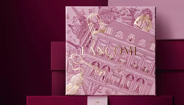 Rosa Lancome-Geschenkbox mit festlichem Muster vor einem burgunderroten Hintergrund.