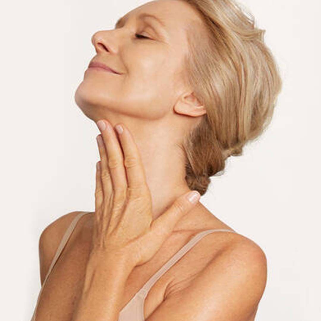 Frau cremt ihren Hals ein