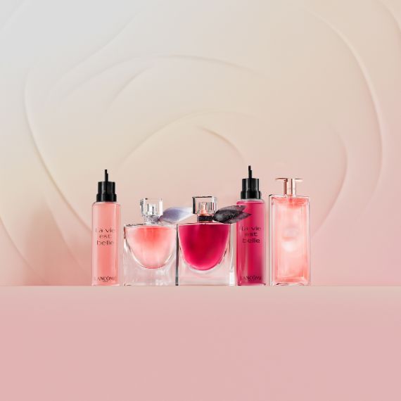 Eine Auswahl an Lancome Parfums und Korperpflegeprodukten der Linien „La Vie Est Belle“ und „Idole“, uberwiegend in Rosatonen, arrangiert auf einem hellrosa Hintergrund mit subtilen Wirbelmustern.