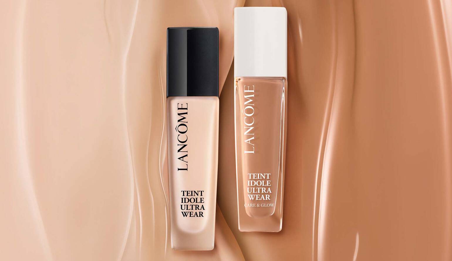 Zwei Flaschchen Foundation von Lancome, Teint Idole Ultra Wear, auf einem Hintergrund aus sanften Hauttonen.