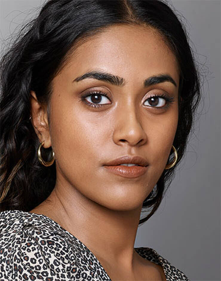 Eine Frau mit dunklen Augen und dunklen Haaren und einem leichten rosa, roten oder blaulichen Hautton