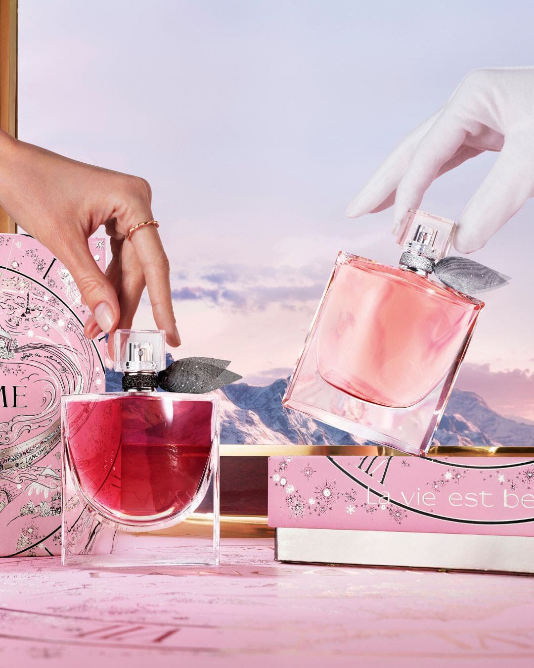 Eine Person tragt mehrere elegante Geschenkboxen von Lancome, die in dunklen Farben mit goldenen Akzenten gestaltet sind.