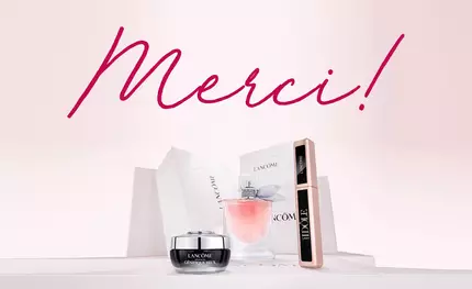 Alt-Text: Eine stilvolle Anordnung von Lancome-Produkten, darunter ein Parfum, eine Creme und eine Mascara, mit dem Schriftzug "Merci!" in pinker Farbe im Hintergrund.
