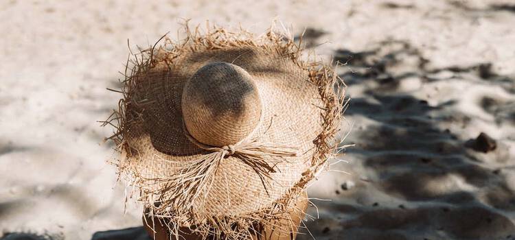 Frau mit Sonnenhut am Strand