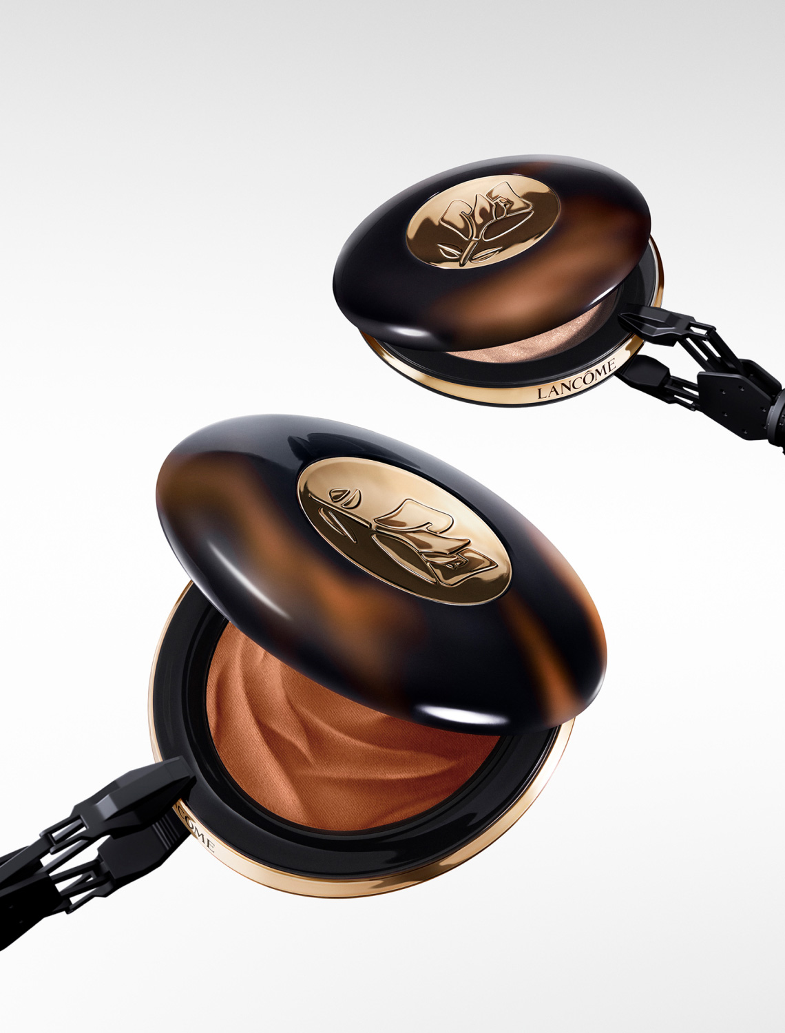 Ein elegantes Makeup-Compact von Lancôme in tortoiseshell-Optik, offen mit samtig-braunem Produkt im Inneren.